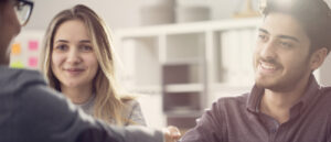 Young couple shaking hands with a female agent