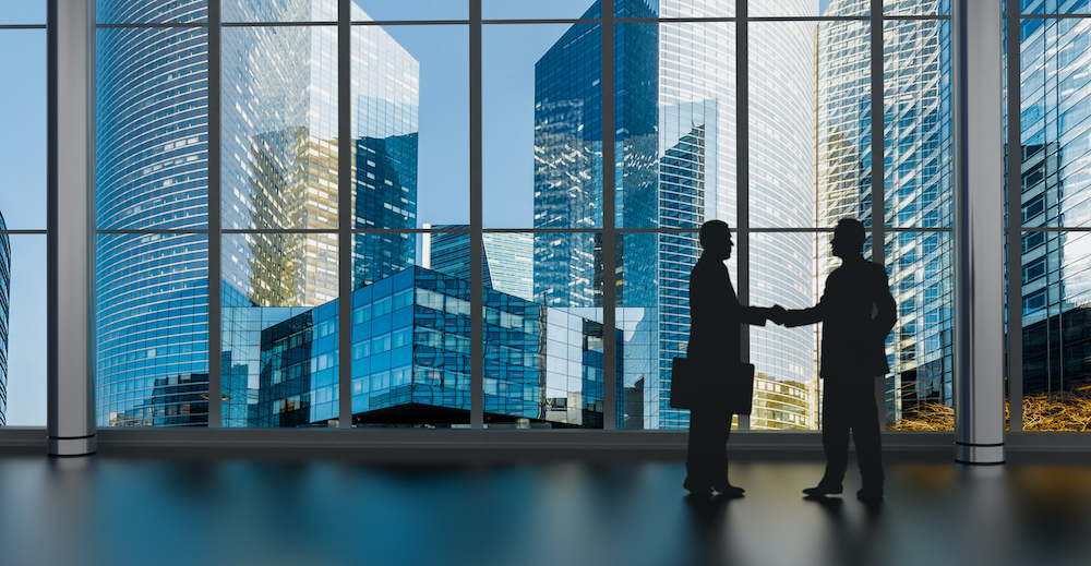 businessman shaking hands inside a business tower