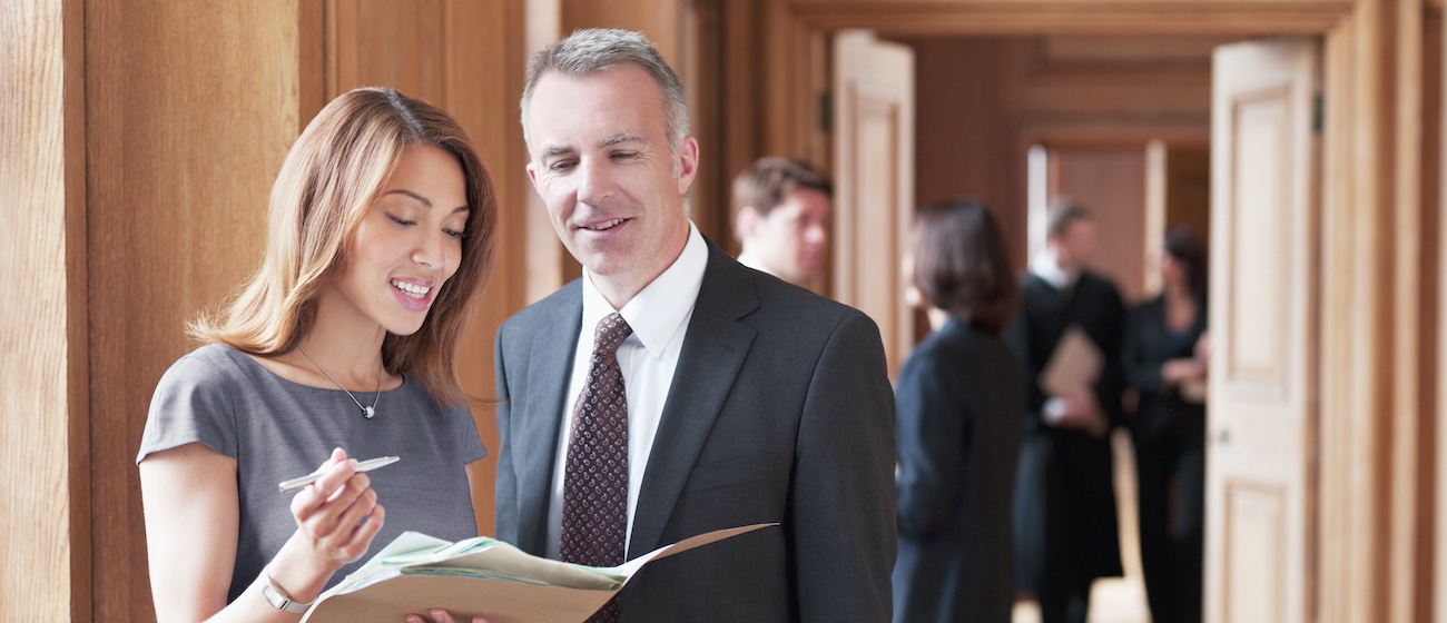 Lawyers reviewing case file in corridor Melbourne Solicitor | Women reviewing a case file with a colleague
